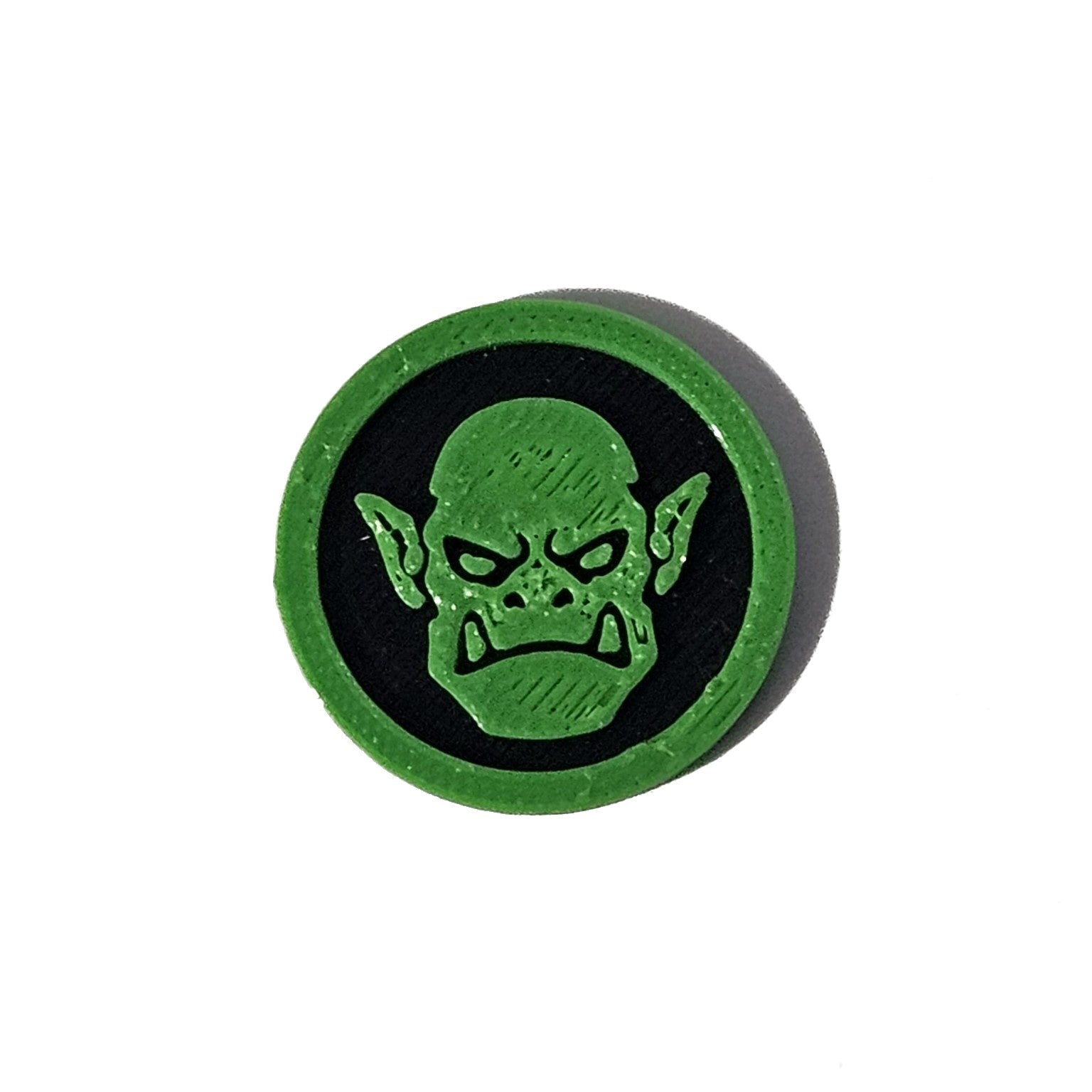 Green and black orc face Halloween token on pure white background